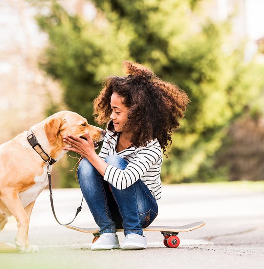 African american girl outdoors on skateboard with her dog